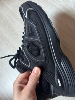 Svarta Dior sneakers med meshdetaljer - Snygga svarta Dior sneakers med coola meshpaneler och reflekterande detaljer. Köpte nyligen och används få gånger och är i väldigt bra skick..