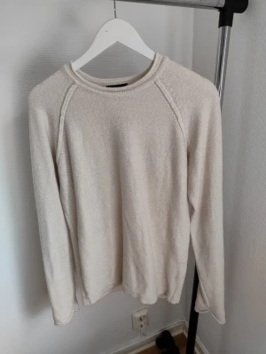 Beige stickad tröja från Selected - Säljer en stilren beige stickad tröja från Selected. Tröjan har rund halsringning, långa ärmar och en diskret struktur i materialet. Perfekt för lager på lager och enkel att matcha med olika outfits.