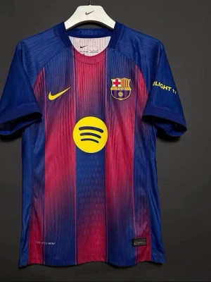 FC Barcelona matchtröja Nike blå/röd - Säljer en officiell FC Barcelona matchtröja från Nike i blått och rött med gula detaljer. Tröjan har klubbmärke, Nike-logga och Spotify-logga på bröstet. Tillverkad i lätt och ventilerande material, perfekt för fotbollsträning eller att bära på läktaren.