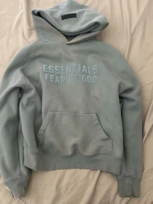 Grön Essentials Fear of God hoodie - Säljer en grön hoodie från Essentials Fear of God med stor logga på bröstet. Äkta, original tags och påse medföljer. Pris kan diskuteras vid snabb affär. Fraktar inom 0-1 dagar!