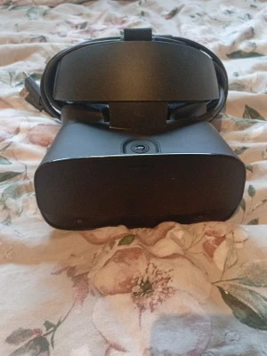 Oculus Rift S VR-headset (Saknar vänstra handkontrollen) - Säljer ett svart Oculus Rift S VR-headset med tillhörande handkontroll. Headsetet har justerbart band och ansluts via kabel. Handkontrollen har joystick, knappar och handledsrem. Perfekt för dig som vill uppleva VR-spel på riktigt.