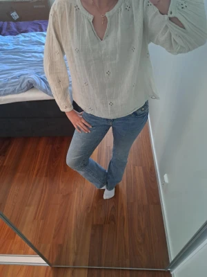 Ljusbeige blus med broderade detaljer - Säljer en ljusbeige blus från ZARA med broderade håldetaljer och avslappnad passform. Blusen har v-ringning med liten knapp och långa ärmar med likadana knappar vid handlederna. Tillverkad i mjuk, luftig bomull som passar perfekt till jeans.🫶