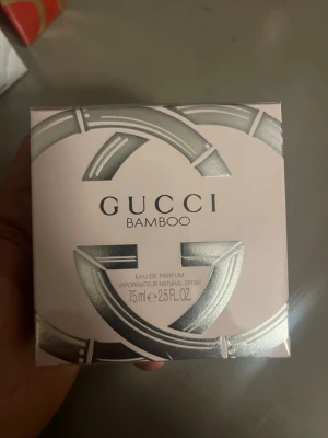 Gucci Bamboo Eau de Parfum 75ml - Gucci Bamboo Eau de Parfum är en elegant parfym i en stilren, ljusrosa förpackning med silverdetaljer och bambuinspirerat mönster. Doften kommer i en 75 ml flaska och utstrålar lyx och modernitet, perfekt för dig som gillar exklusiva dofter.