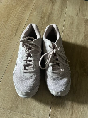 Ljusrosa idrottsskor - Säljer ett par ljusrosa idrottsskor med detaljer och snörning. Skorna har en sportig design med ventilerande meshmaterial på ovansidan och en flexibel, vit sula. Perfekta för träning eller en aktiv vardag.