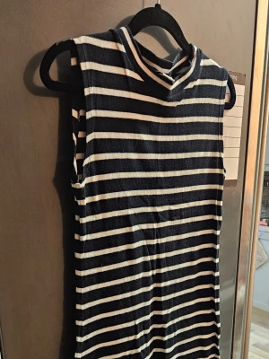 Randig ärmlös klänning Lindex - Snygg ärmlös klänning från Lindex med marinblå och vita horisontella ränder. Klänningen har en enkel, rak passform och mjukt ribbat material som känns bekvämt mot huden. Perfekt för en avslappnad och trendig look.
