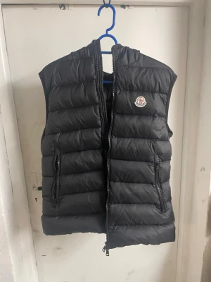 Moncler väst med luva - Säljer nu min moncler väst. Börjar bli för liten för mig. Endast använd fåtal gånger. Står storlek 3 i den tror det är en medium nästan large. Jag har inget kvitto eller liknande på den. 