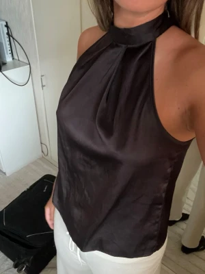 Svart topp i satin - Snygg svart topp i glansigt satinmaterial. 