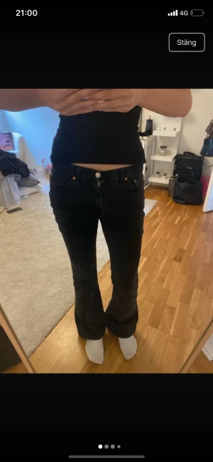 Svarta bootcut jeans - Säljer ett par svarta bootcut jeans med klassisk femficksmodell och knappgylf. Jeansen har en lätt utsvängd passform nedtill och sitter snyggt över höfterna. Perfekta till en trendig vardagslook. Jeansen är lite ur tvättade men annars bra skick!