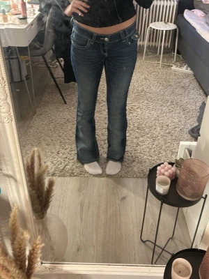 Blå bootcut jeans med kontrastsömmar - Säljer ett par blå bootcut jeans med snygga kontrastsömmar och låg midja. Jeansen har unika fickor. Perfekta för dig som gillar en avslappnad men trendig stil. Pris kan diskuteras 