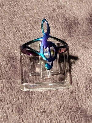 Regnbågsfärgad ring med g-klav - Cool ring i metall med en regnbågsfärgad finish och en stor g-klav-symbol framtill. Perfekt för dig som älskar musik och vill sticka ut med en unik accessoar. Ringen har en öppen design och skimrar i blått, lila och grönt.