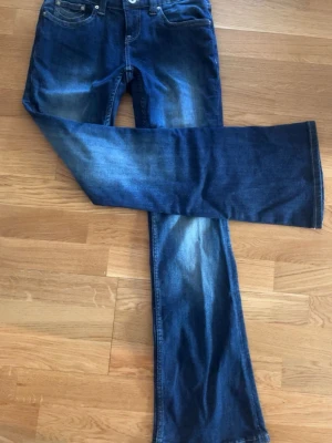 Blå bootcut jeans med slitningar - Helt oanvända! Säljer ett par blå bootcut jeans med snygga slitningar. Jeansen har utsvängda ben och kontrastsömmar på bakfickorna. 