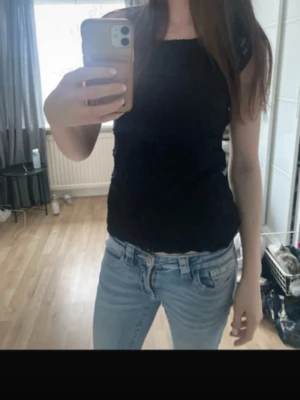 Svart spetsblus med kort ärm - Säljer en svart blus med korta ärmar i spets. Toppen har en figurnära passform och är tillverkad i ett tunt, genombrutet spetsmaterial som ger en snygg och elegant look. Perfekt att styla med jeans eller kjol.