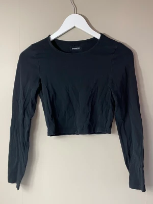 Svart croppad långärmad topp - Snygg svart croppad topp från even&odd (köpt på zalando) med långa ärmar och rund halsringning. Tillverkad i mjukt stretchigt material som sitter bekvämt. Perfekt att matcha med höga jeans eller kjol. Passar mig som har storlek S.