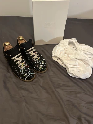 Maison Margiela skor  - Hej! Säljer nu mina favorit skor Maison Margiela paintsplatter! Har användts blandannat av mig i över ett år och säkert 10 personer mer. Dessa har en lång historia och har varit med om en hel del! Har fått många komplimanger och kommentarer! Skorna är väldigt slitna men väldigt bekväma och fullt användbara och inge vatten läcker igenom sulan! Skorna är nytvättade, har fått heelpatches vid hälen och är redo för nästa användare! Varmt välkommen att höra av dig vid minsta intresse av köp! Mvh 😁