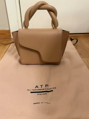 Beige handväska från ATP Atelier - Säljer nu min fina ATP väska med kringlat band i topp skicka. Tyvärr inte funnit tillfällen för användning och säljer därför vidare, hör av dig vid frågor!
