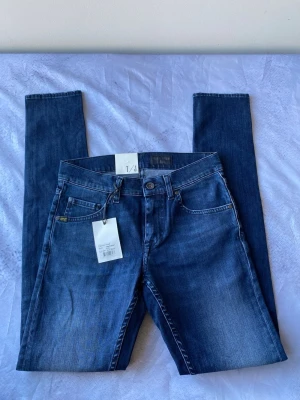 Blå jeans från Tiger of Sweden - w29/L32 - Snygga blå jeans från Tiger of Sweden med klassisk femficksmodell och raka ben. Jeansen har en djupblå tvätt med subtila slitningar och är tillverkade i ett mjukt bomullsmaterial. Perfekta för dig som gillar stilrena och tidlösa jeans.