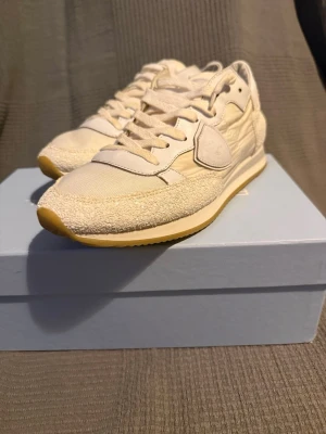 Philippe model  - Snygga beige sneakers från Philippe model med ovandel i mocka och textil. Skorna har en låg siluett, ton-i-ton snörning och gummisula i ljusgul nyans. Klassisk design med diskret logga på sidan och detaljer i olika material för en modern look.