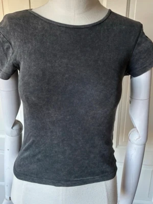 Mörkgrå tight t-shirt i bomull - Snygg mörkgrå t-shirt med tvättad look och tight passform. Tillverkad i mjuk bomull och har klassisk rund halsringning samt korta ärmar. Säljer pga att den inte används och storleken kan upplevas som xxs/xs💓