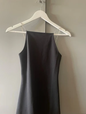 Svart klänning med pärlband H&M XS - Säljer en svart kort klänning från H&M i storlek XS. Klänningen har raka linjer och tunna axelband dekorerade med pärlor för en extra snygg detalj. Perfekt till sommarens alla tillfällen!