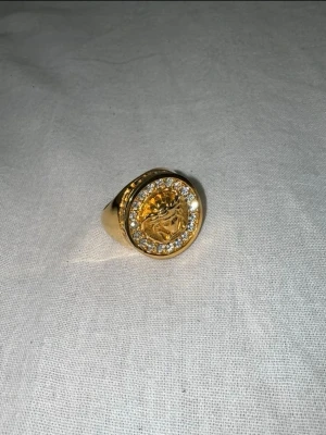 Versace/Medusa guld pläterad ring - En aldrig använt guldpläterad ring med fina vvs liknande diamanter runt om som glänser.  Finns att hämta i Malmö men kan även frakta!