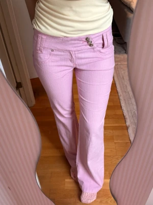 Ljusrosa bootcut jeans/byxor med knappar - Säljer ett par ljusrosa jeans/byxor med bootcut passform och låg midja💓de har ett mjukt material!