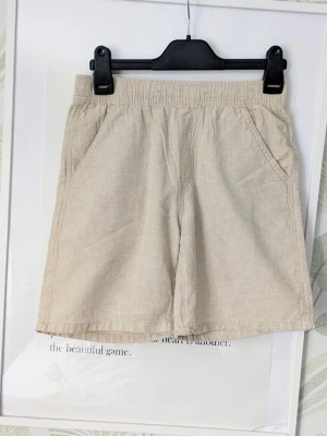 Shorts Linneshorts Lindex Storlek 146 - - Shorts i linnemix.  - Använd en gång vid skolavslutning så i nyskick.  - Det är svårt att få exakta färgen men första och sista bilden stämmer nog bäst överens med färgen, de är ljusbeigea.  - Jag kan ha missat någon miniskavank men jag har försökt att granska plagget så gott det gårr.