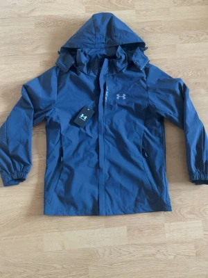 Blå regnjacka från Under Armour - Storlek M men passar S