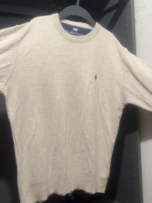 Beige stickad tröja från Polo Ralph Lauren - Klassisk beige stickad tröja från Polo Ralph Lauren med rund halsringning och diskret broderad logga på bröstet. Tröjan har långa ärmar och är tillverkad i ett mjukt, tunt material som passar perfekt till lager-på-lager-stil. Size L men passar M 🔥 Referens: 172 cm / 70 kg