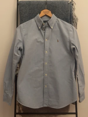 Ljusblå skjorta från Polo Ralph Lauren - Grym kvalité, äkta Oxford 100% bomull. Postar alltid dagen efter senast. Axelmått: 41 cm längd: 66 cm. Storlek M