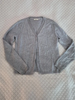 Simpel grå cardigan - Söt grå kofta med v-ringning och ribbade ärmslut. Storlek 146/152 eller XXS. Har några noppror men ger ett fint helhetsintryck!💘