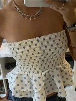 Vit prickig volang tubtopp - Supersöt vit tubtopp med ljusblå prickar och volangkant. Smockad överdel som sitter bekvämt och ger en snygg passform. Perfekt för varma dagar och kan bäras både med och utan axelband. Lätt och luftig känsla. Kan även användas som kjol❤️