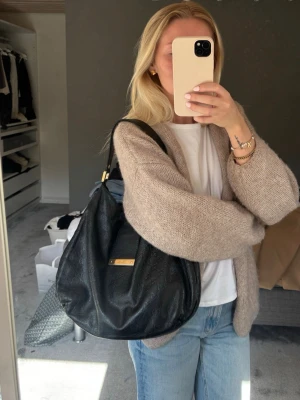 Gucci guccissima hobo bag, black  - Säljer en svart axelväska från Gucci i mjukt läder med diskret GG-mönster och guldfärgad metallbricka framtill. Väskan har en avslappnad, rundad form och bred axelrem för skön komfort. Väskan är äkta och köpt från A Retro Tale, med kommer dust bag också. Finns bevis och serie nummer i väskan 