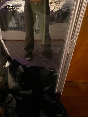 Ljusgröna bootcut jeans - Säljer ett par ljusgröna jeans med bootcut passform och låg midja. Jeansen har fickor fram samt en liten detaljficka på ena sidan. Perfekta för dig som vill ha en avslappnad men ändå trendig look.