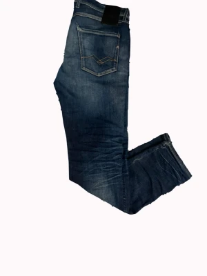 Mörkblå Replay jeans med tvätt - Snygga mörkblå Replay jeans i modellen Anbass hyperflex. Jeansen sitter slim och har klassiska fem fickor och kontrastsömmar på bakfickorna. Tillverkade i denim med en tvättad look som ger en avslappnad vibe. Storlek 30/30