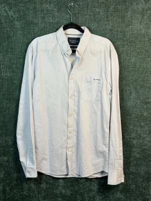 Vit skjorta från Bondelid - Klassisk vit skjorta från Bondelid med bröstficka och diskret broderad logga. Skjortan har lång ärm, knappar framtill och en snygg krage. Perfekt till både jeans och chinos för en clean look.