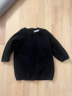 Svart stickad tröja från Zara - En enkel och stilren svart stickad tröja från Zara. Tröjan har rund halsringning, långa ärmar och ribbade muddar vid ärmslut och nederkant. Perfekt basplagg till garderoben och lätt att matcha med olika outfits.