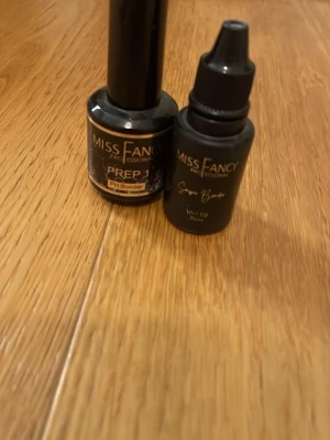 Miss Fancy PH bonder & super bonder - Två flaskor nagelprodukter från Miss Fancy. Ena är en PH Bonder Prep och den andra är en svart flaska med UV/LED-funktion. Båda har en stilren, matt svart design och är perfekta för dig som vill fixa snygga naglar hemma.