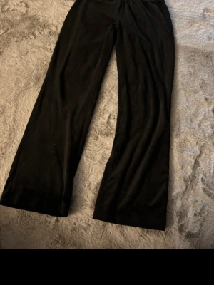 Svarta mjukisbyxor från Gina Tricot - Säljer ett par svarta mjukisbyxor från Gina Tricot med rak passform och resår i midjan. Tillverkade i ett mjukt och bekvämt material som passar perfekt för chill dagar. Enkla att matcha med olika toppar för en avslappnad look.