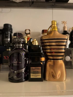 Tom ford o några andra - Säljer tre lyxiga parfymer: Tom Ford Tuscan Leather i svart glasflaska med guldetikett, Jean Paul Gaultier Le Male Le Parfum i guldig kroppformad flaska och Lattafa Khamrah i mörklila dekorativ flaska med metalliska detaljer. Perfekt för dig som gillar unika dofter.