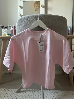Ljusrosa t-shirt från Emmie star - En basic ljusrosa t-shirt från Emmie star med klassisk rund halsringning och korta ärmar. Tillverkad i mjuk bomull som känns skön mot huden. Perfekt för en enkel och stilren look.