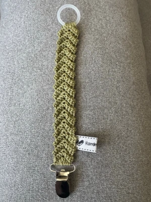 Virkad napphållare - Virkad, khakigrön napphållare, virkad av mig i 100% bomullsgarn med metallclips och silikonring.  Mönsterskapare: animo.design
