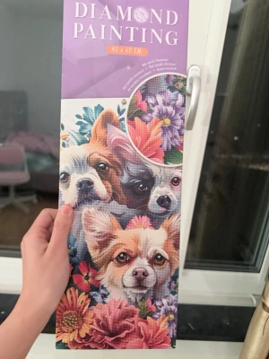 Diamond painting 40x60 cm hundmotiv - Diamond painting-kit med måtten 40x60 cm. Motivet föreställer två hundar bland färgglada blommor. Förpackningen innehåller canvas, verktyg och färgade stenar. Perfekt för dig som gillar pyssel och kreativa projekt.