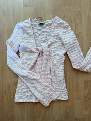 Ljusrosa strukturerad knytkofta - Supersöt ljusrosa kofta med knyt framtill. Säljs inte längre hos Gina så har ingen koll på vad jag köpte den för, så pris går att diskutera. Jätte fin med ett vitt linne under!!