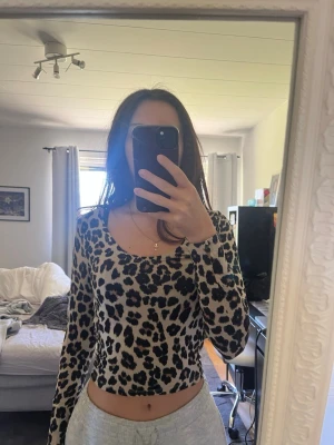 Leopardmönstrad croppad topp - croppad topp med leopardmönster och lång ärm. Toppen har en rundad urringning och sitter tight mot kroppen.