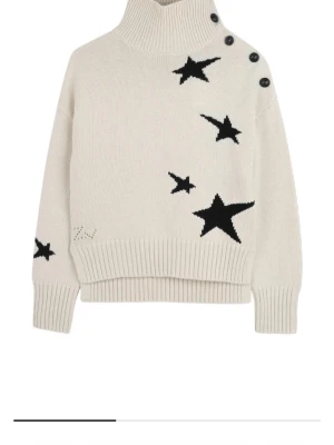 Zadig&Voltaire tröja - Snygg beige stickad tröja med svarta stjärnor från Zadig&Voltaire. Polokrage och dekorativa svarta knappar längs axeln ger en cool detalj. Säljer pågrund av att den inte kommer till användning💖pris kan alltid diskuteras!