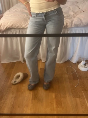 Ljusblå raka jeans - Säljer ett par ljusblå jeans med rak passform och klassisk femficksdesign. Jeansen har låg midja och stängs med knapp och dragkedja. Perfekta för en avslappnad och trendig look.