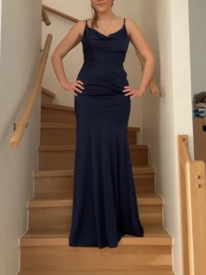 Marinblå balklänning bubbleroom - Elegant marinblå långklänning med smala axelband och figurnära passform från bubbleroom. Säljer då detta inte va klänningen för mig. Helt ny. Klänningen har en mjukt draperad urringning och faller snyggt längs kroppen. Perfekt för speciella tillfällen som till exempel balen där du vill känna dig extra uppklädd. Tyget är mycket stretchigt. Hör gärna av er för mer info💓