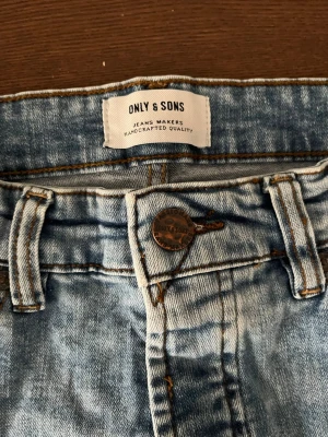 Ljusblå jeans från Only & Sons - Snygga ljusblå jeans från Only & Sons med klassisk femficksdesign och knappgylf. Jeansen har en tvättad look och raka ben. Perfekta för en avslappnad stil och tillverkade i bomull för skön komfort.