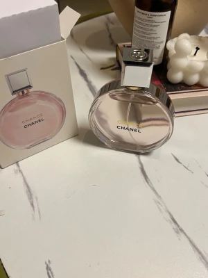 Chanel Chance Eau de Parfum 100ml - HELT FULL!!!Chanel Chance Eau de Parfum i en rund, transparent glasflaska med silverfärgad metallkork och detaljer. Doften har en ljus rosa nyans och flaskan är elegant med tydlig Chanel-logga. Perfekt för dig som gillar exklusiva och klassiska parfymer.