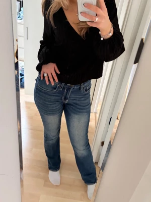 Blå bootcut jeans med broderade fickor - Säljer ett par blå bootcut jeans med snygga broderade detaljer på bakfickorna och kontrastsömmar. Jeansen har normal/låg midja och är stretchiga. Supercoola och sköna som passar till allt. Jättesnygga detaljer som gör dem mer unika och coola. Köpte i USA (konstig storlek~ca M/38) och har använt dem ett par gånger, därför är den lite slitna där nere. Älskar dem men har för många jeans…😞 Passar till vardags men också snygga till fest! Hör av er vid frågor!💕